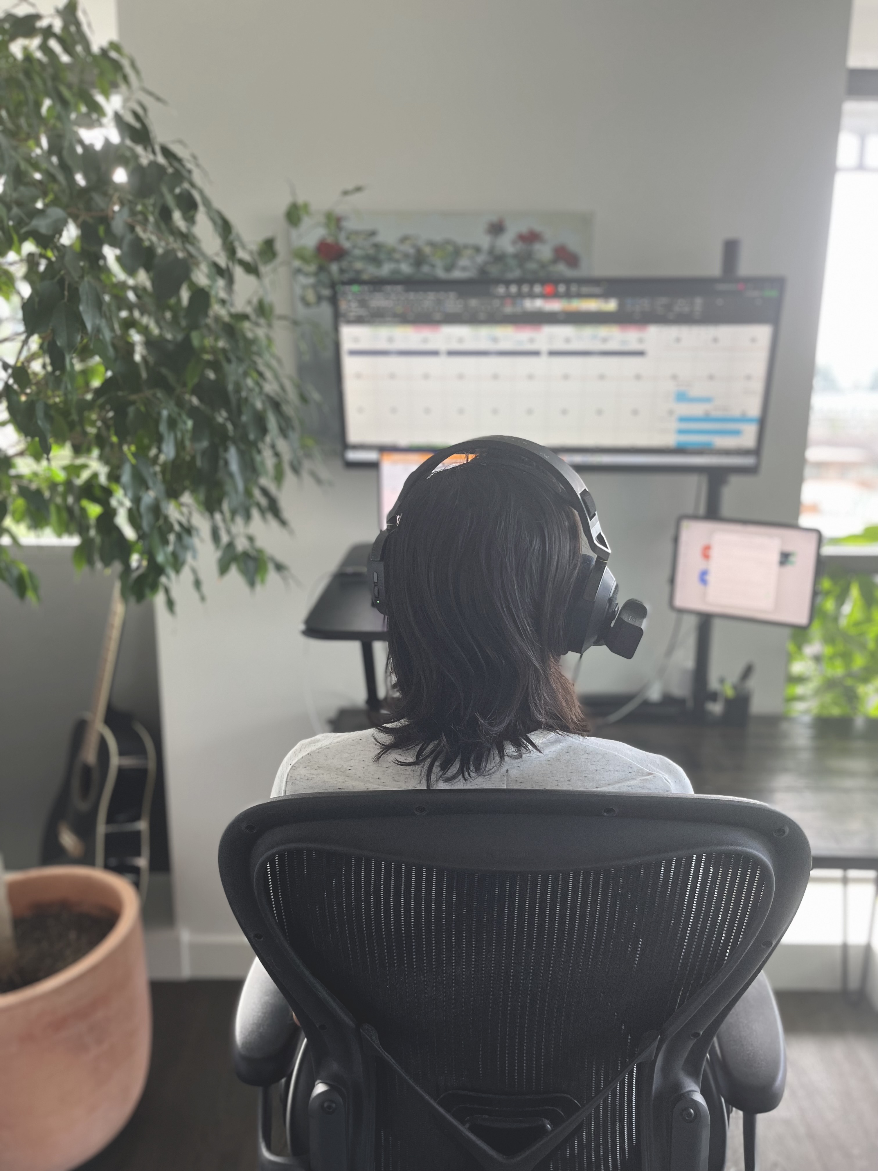 A shot from behind Noah in Easy Surf’s home office. He’s sitting in his desk chair and testing a page with is headmouse and speech recognition software. He’s wearing a white t-shirt and has dark brown, shoulder-length hair.