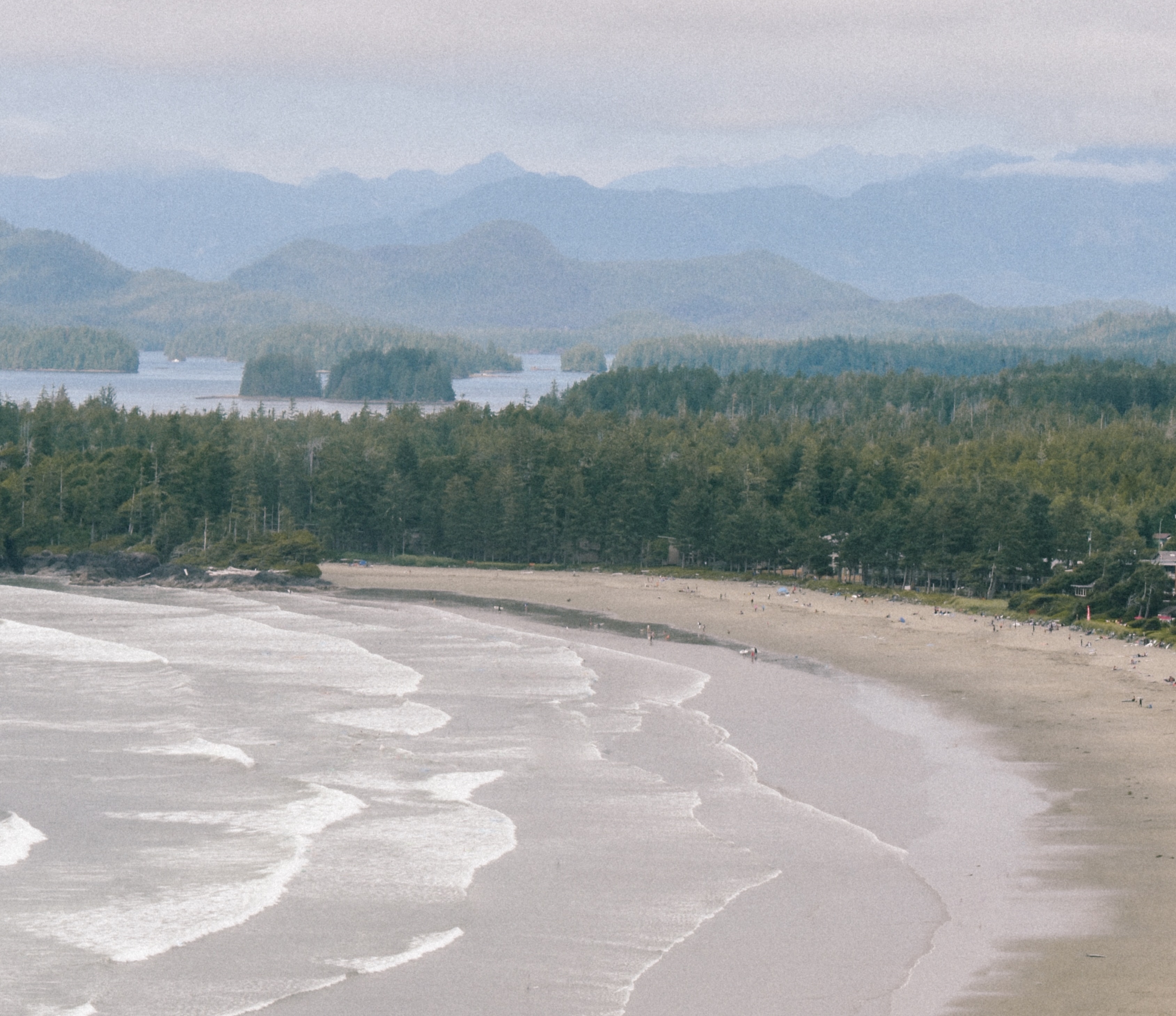 A bird's-eye-view of Chesterman beach and the pine trees and mountains surrounding it in Tofino, British Columbia.